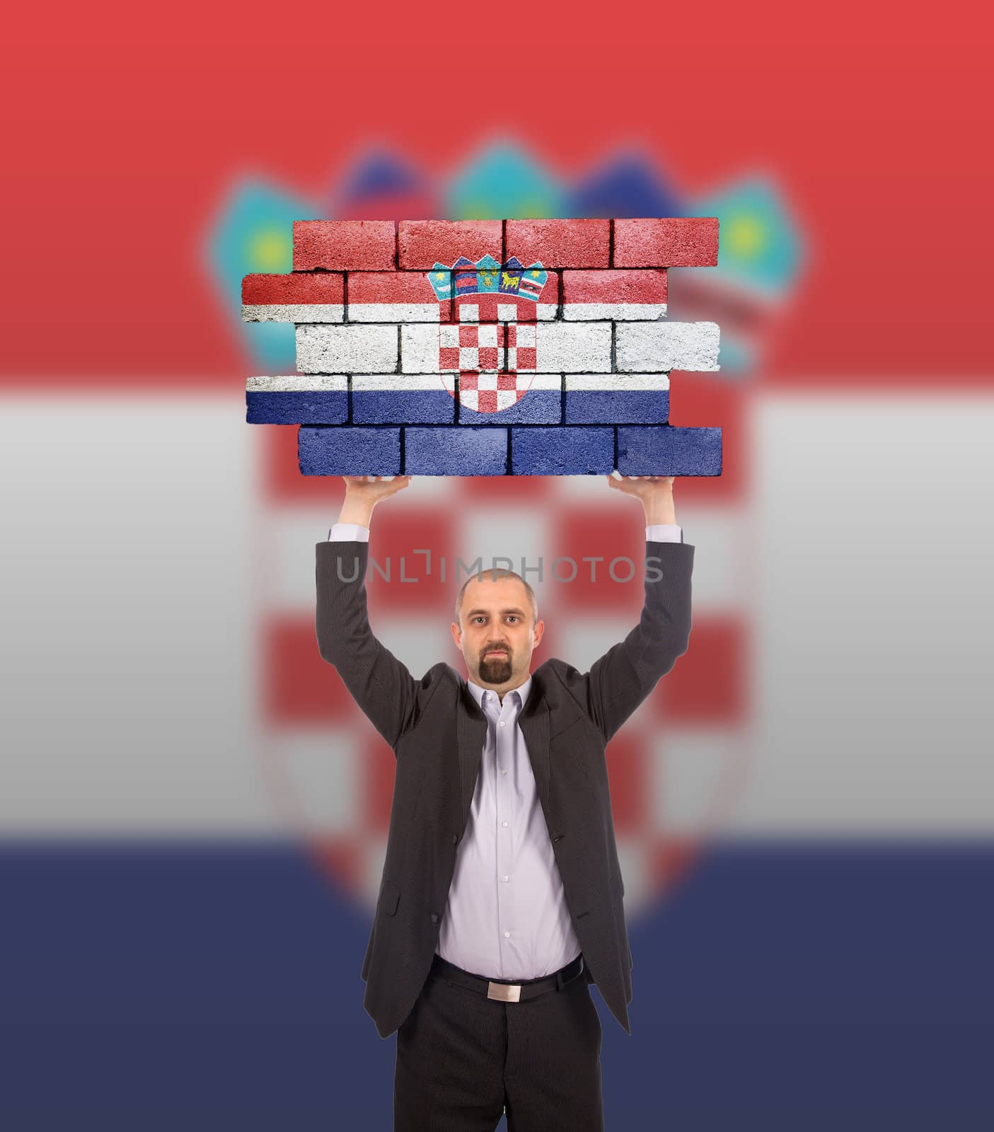 Businessman holding a large piece of a brick wall by michaklootwijk