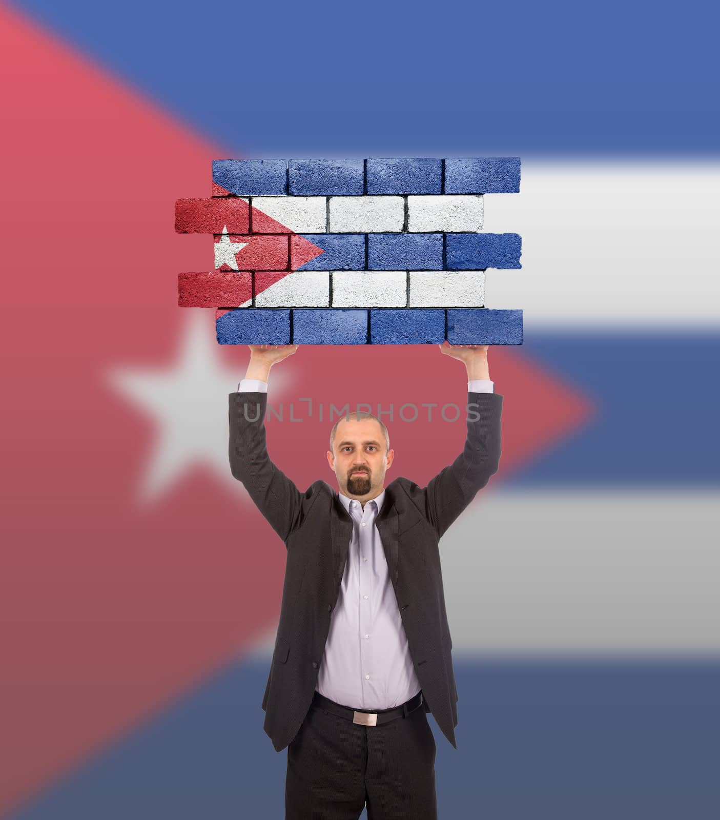 Businessman holding a large piece of a brick wall, flag of Cuba, isolated on national flag