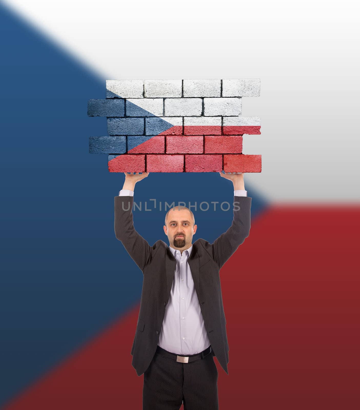 Businessman holding a large piece of a brick wall by michaklootwijk