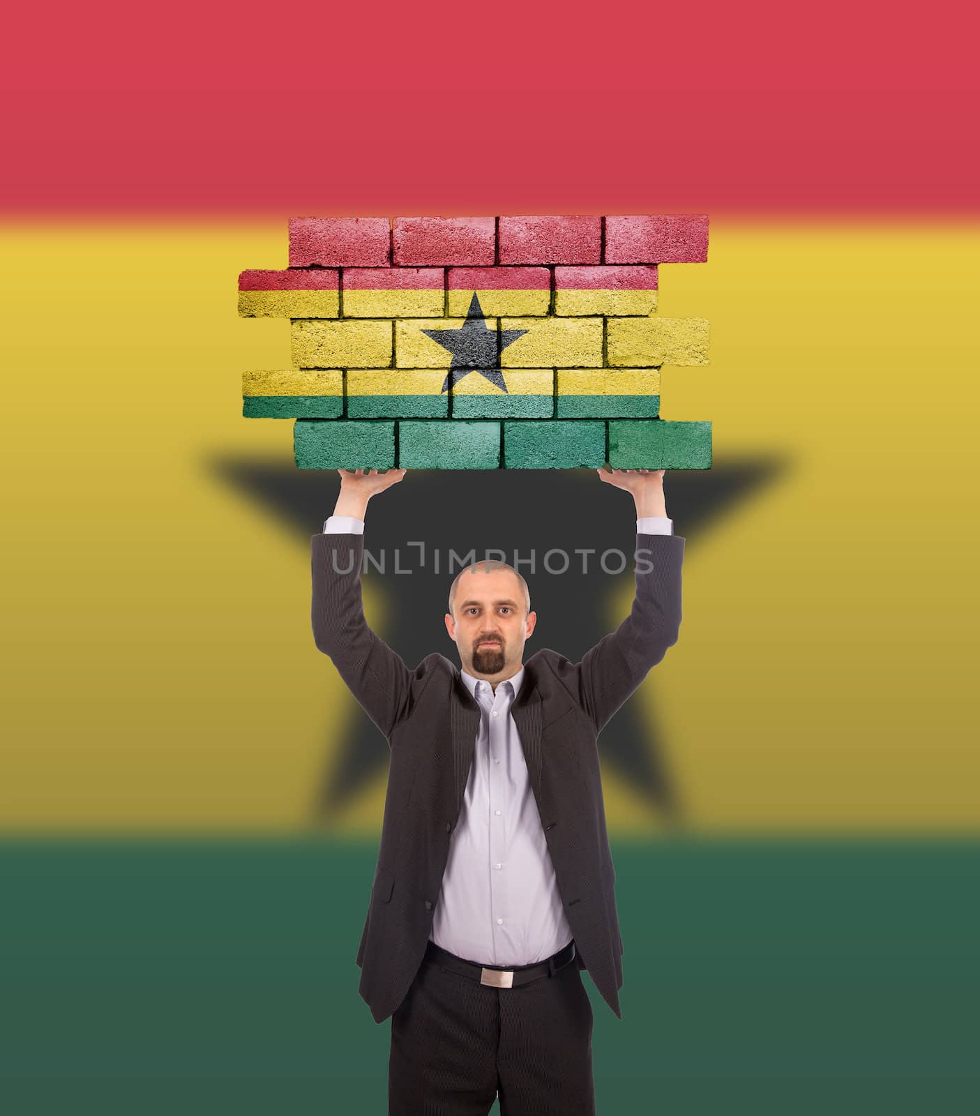 Businessman holding a large piece of a brick wall, flag of Ghana, isolated on national flag