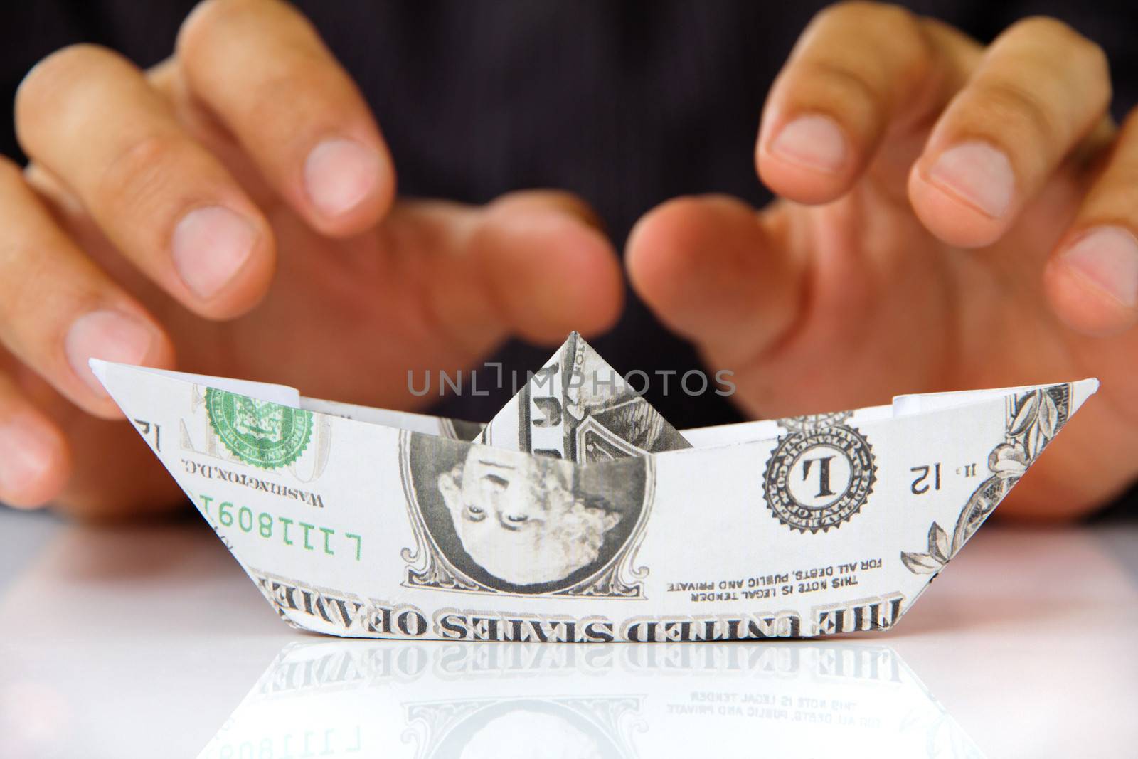 hand holding origami paper sailboat, money concept