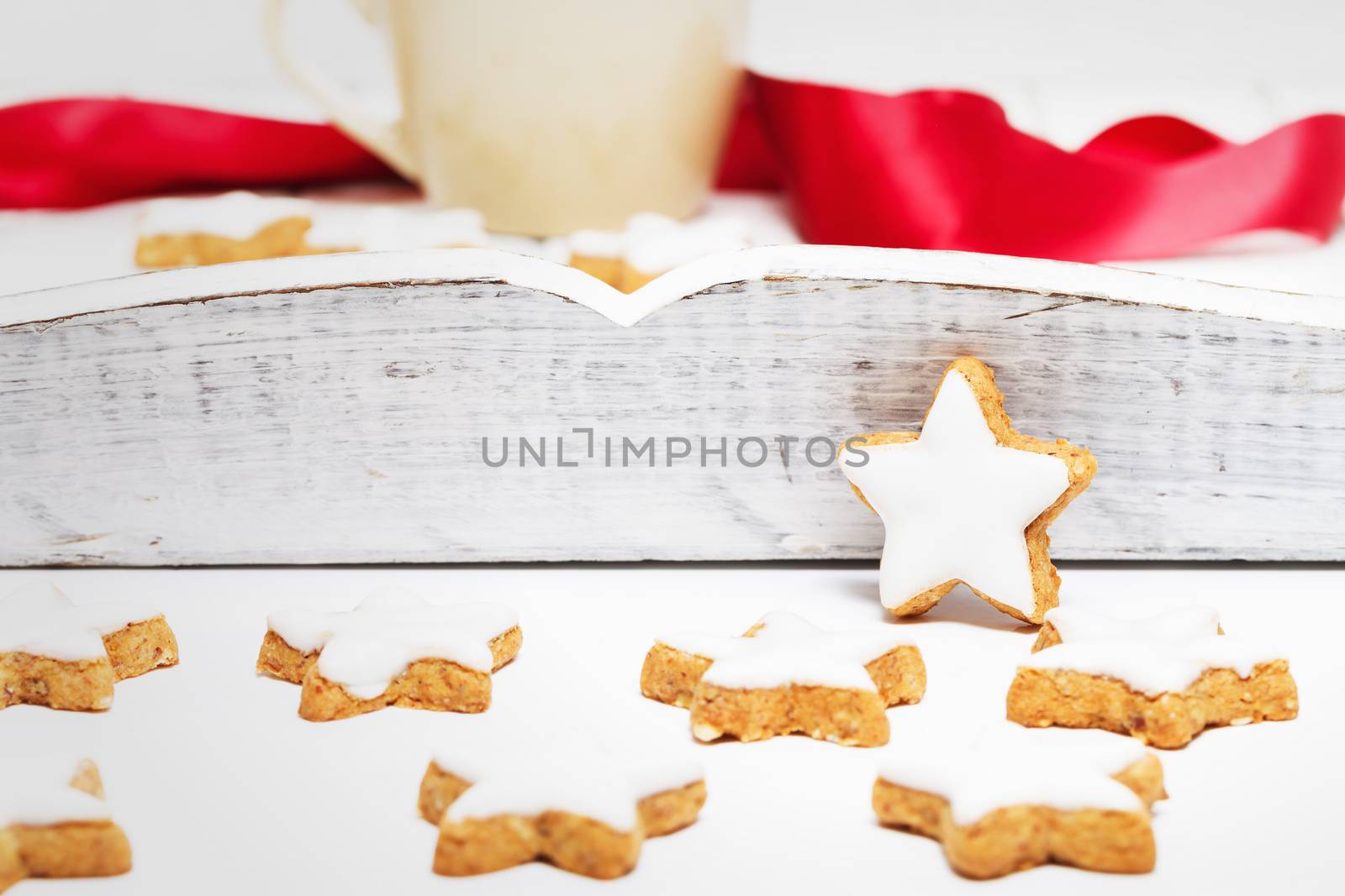 cinnamon stars in front of a white wooden tray with a coffee cup and a red ribbon