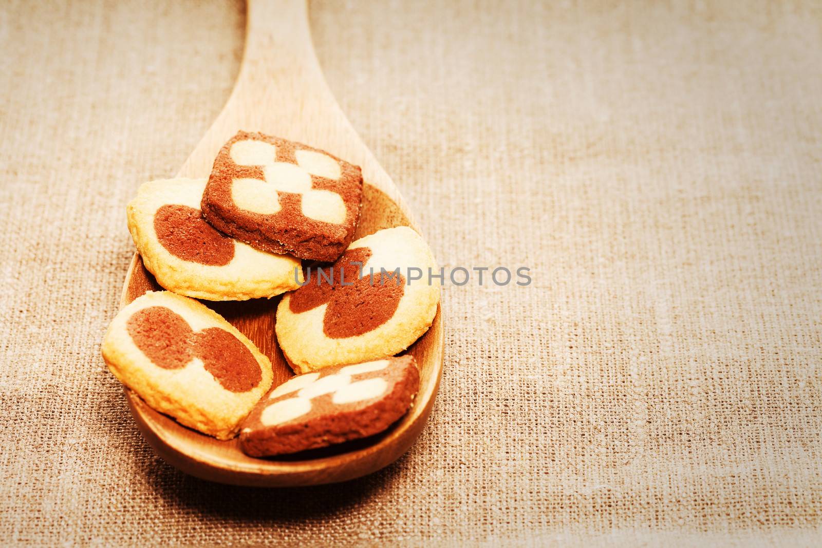 closeup of christmas cookies on a wooden spoon on linen fabric