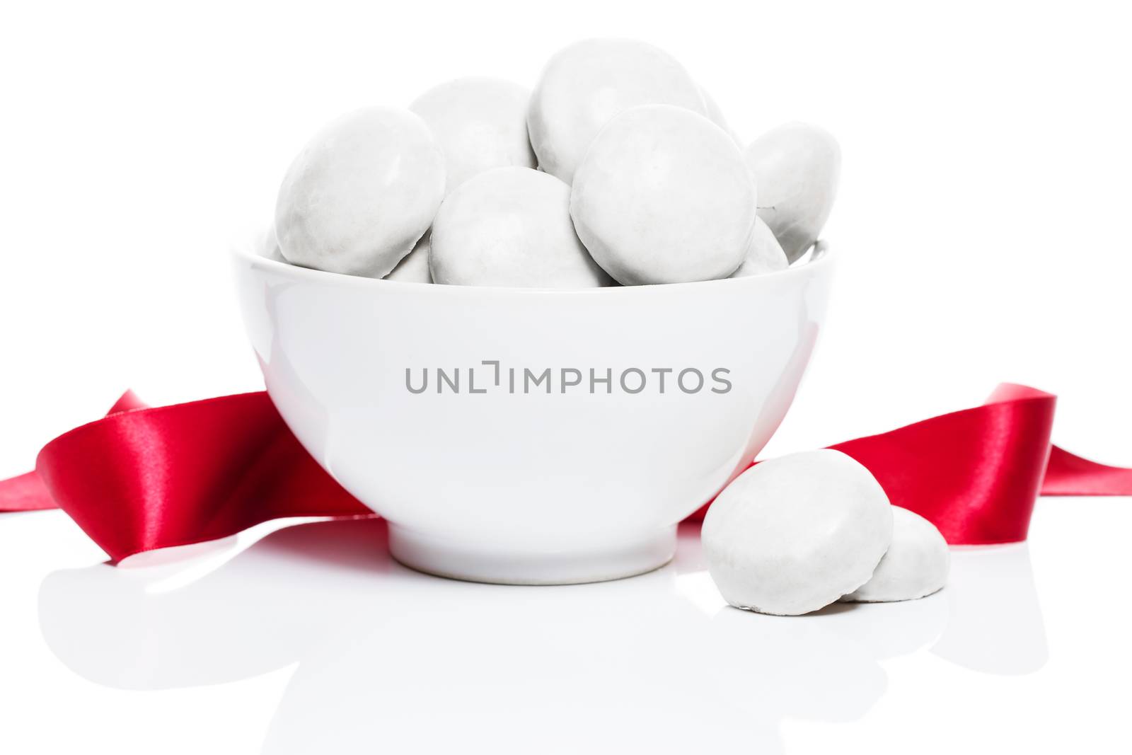 white gingerbread lebkuchen cookies with sugar icing in a white bowl with a red ribbon on white background