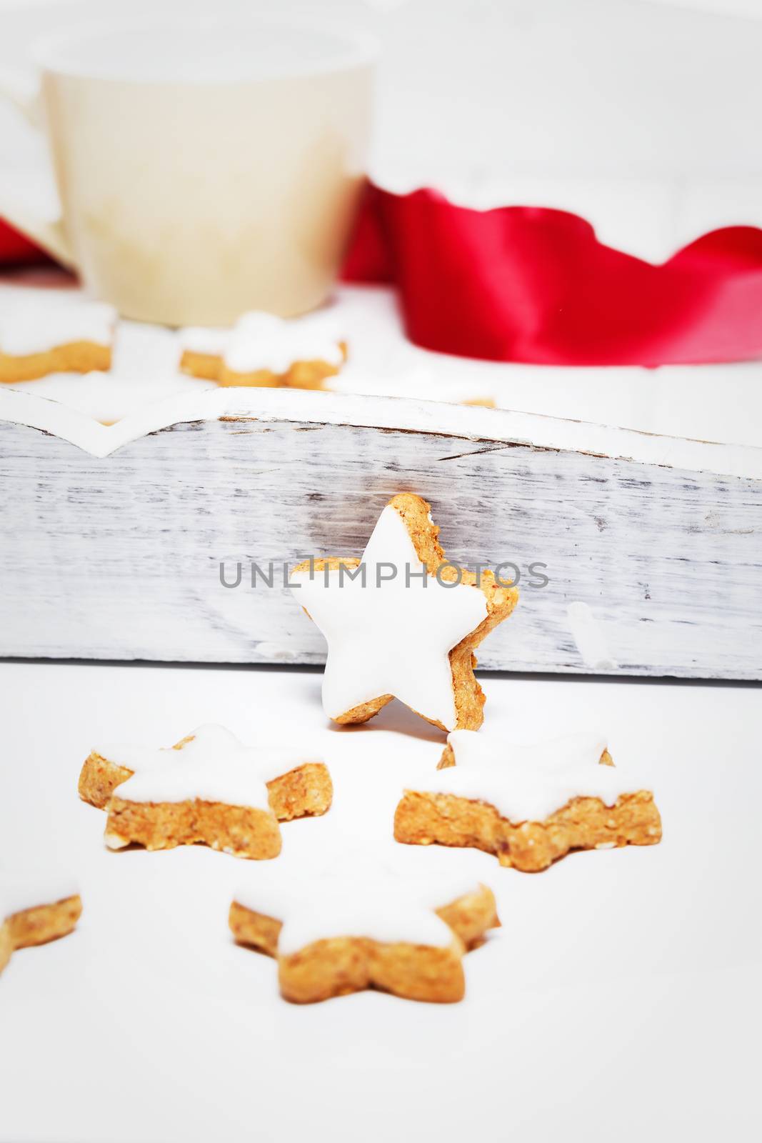 cinnamon stars for christmas in front of a white wooden tray with a cup and a red ribbon