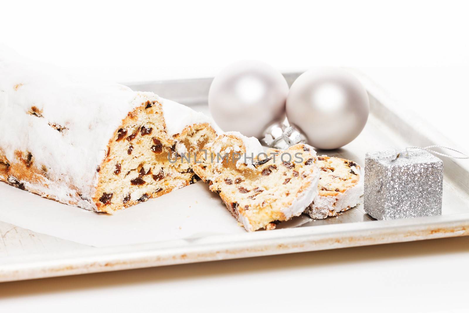 stollen cake for christmas on a silver metal tray with a silver christmas balls and small christmas present