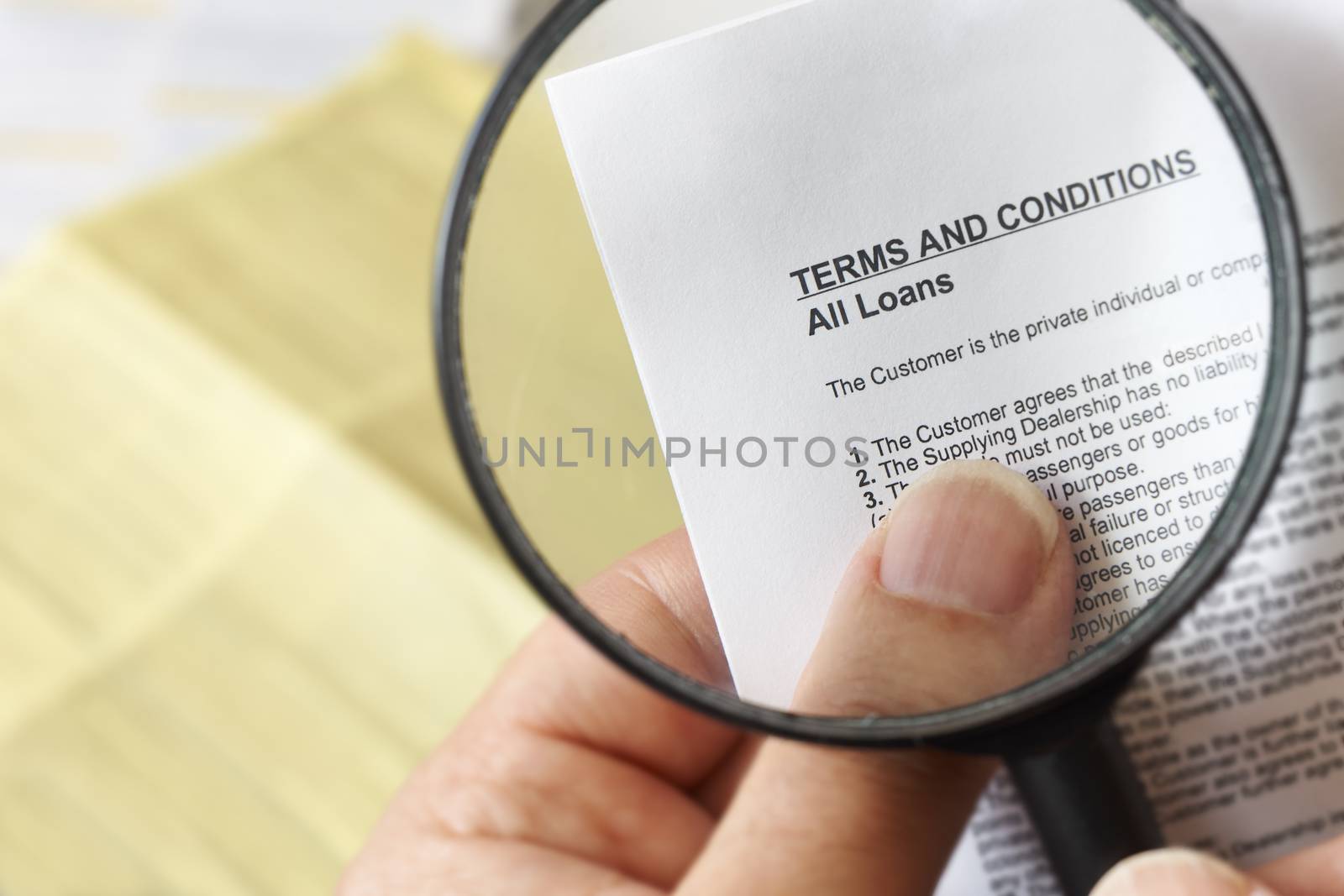 hands holding magnifying glass reading terms and conditions of loan agreement