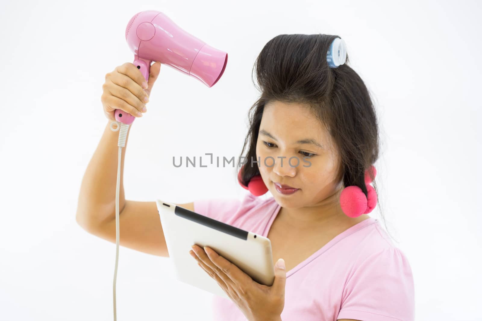 pretty young adult woman with hair dryer using tablet as mirror