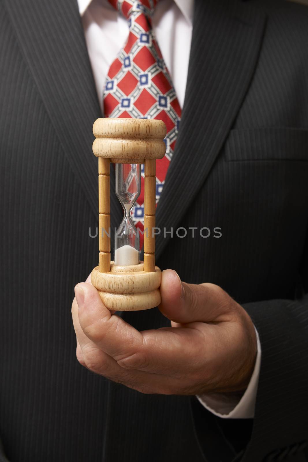 businessman holding hourglass towards camera with space for copy