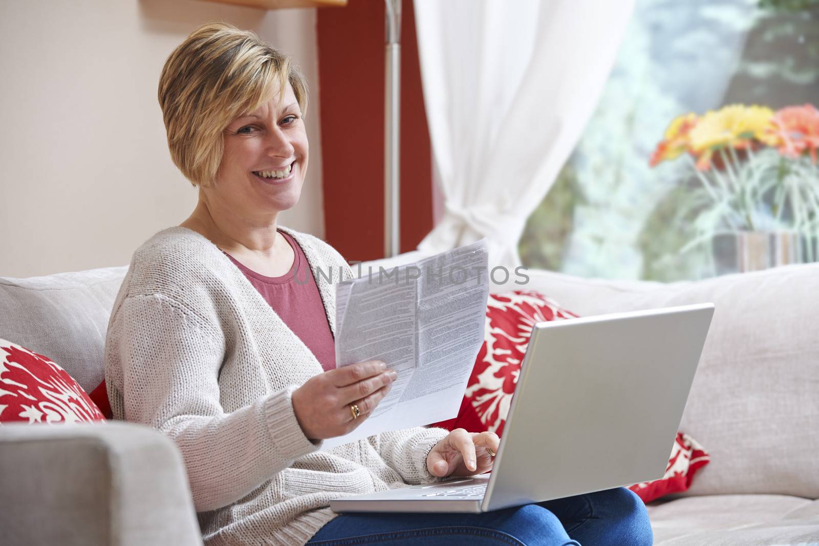 Woman looking happy while sitting at home doing home banking with laptop