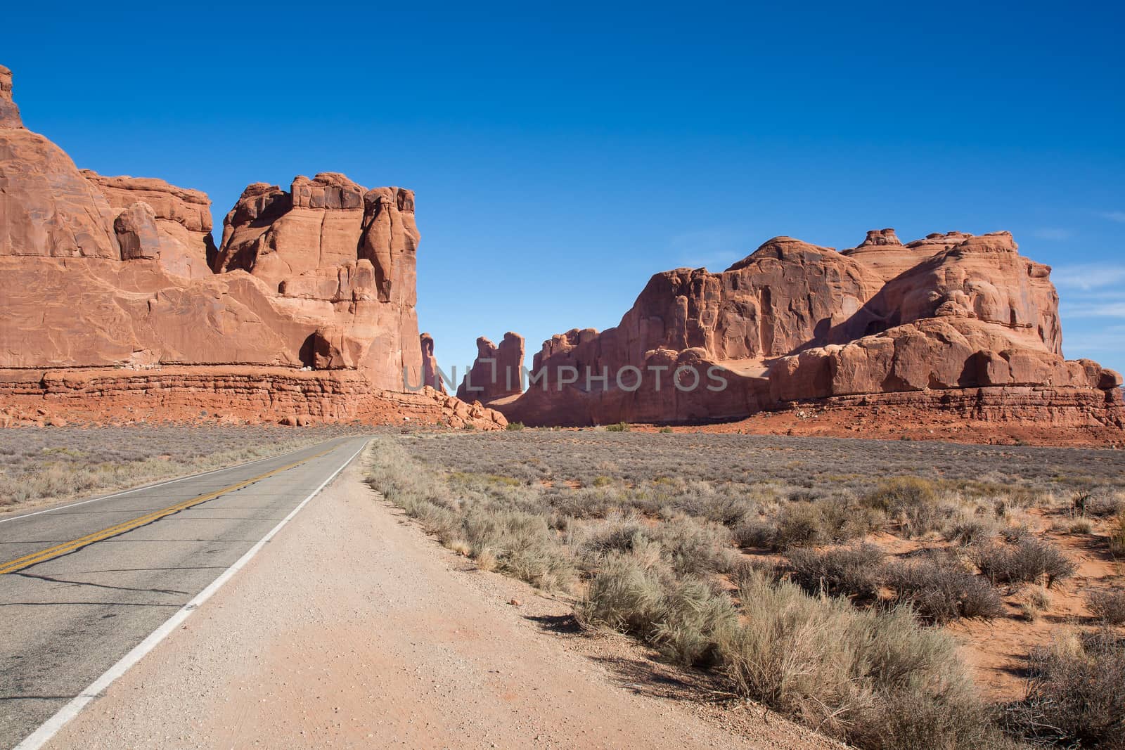 This image shows the drive into Arches where huge rock formations seem to have been thrust  upward from the ground.