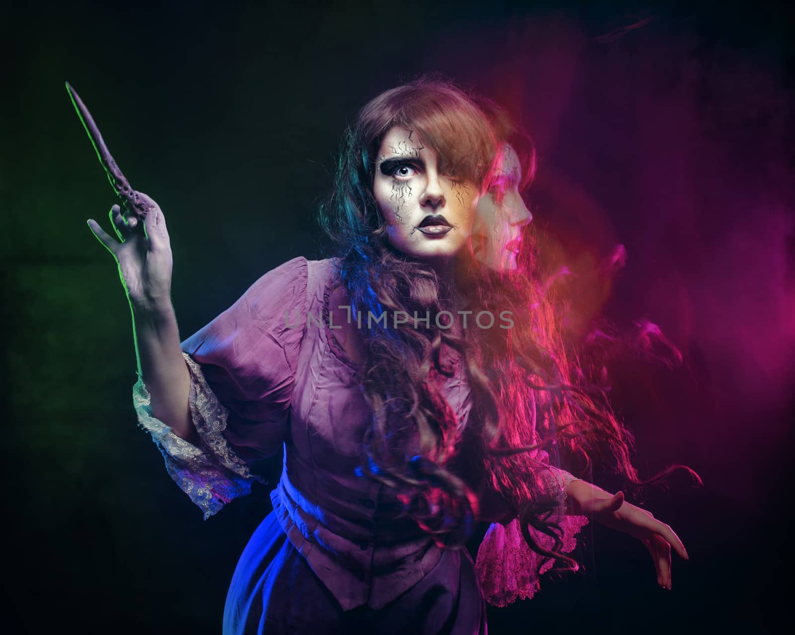 Girl in the image of a witch with a magic wand shot in studio