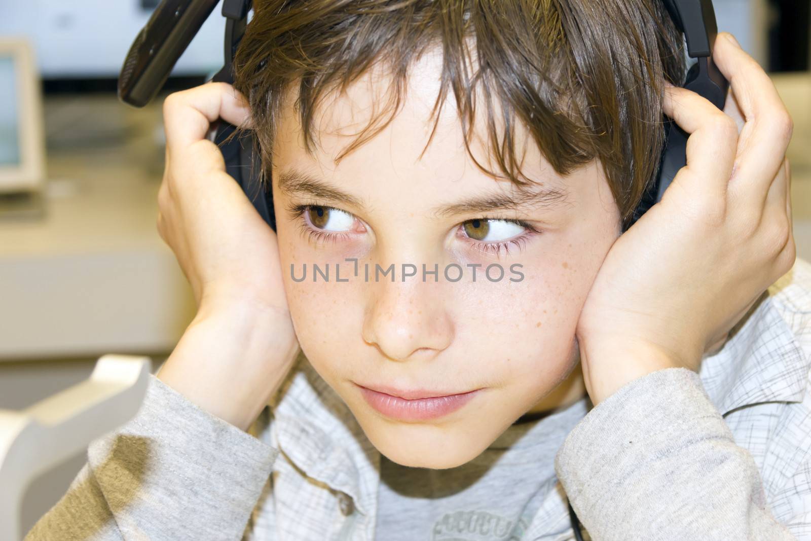 Portrait of a sweet young boy listening to music on headphones  by Tetyana