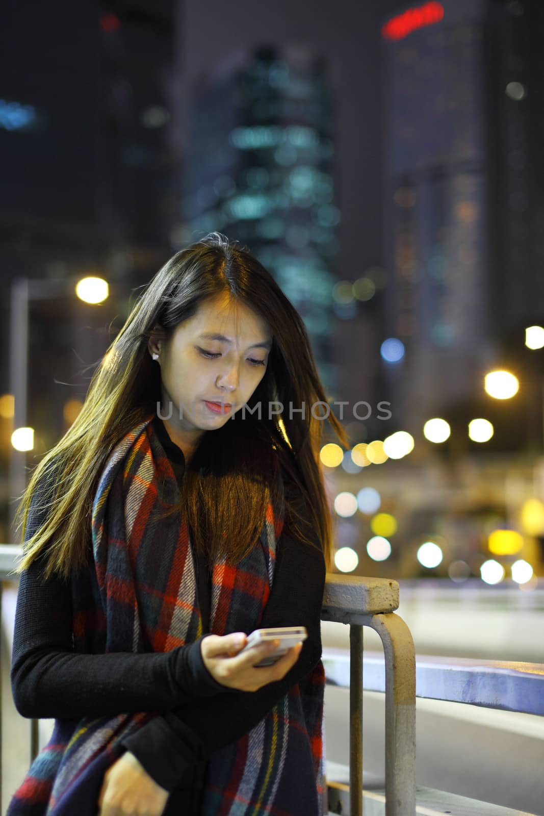 woman use mobile phone in city at night by leungchopan