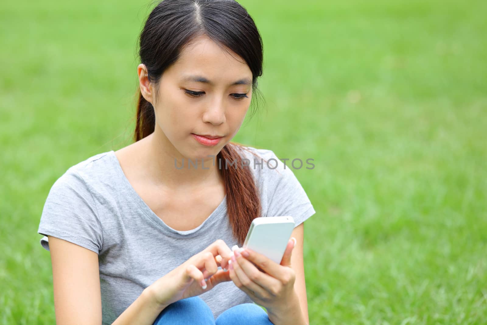 Asian woman using smartphone on grass