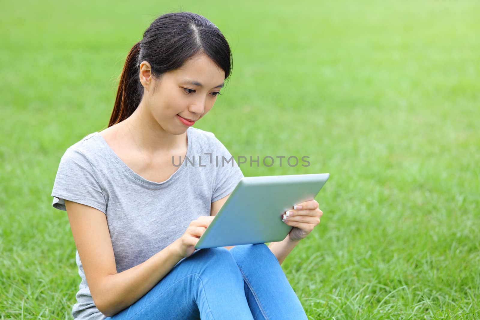 Woman sitting on grass with tablet computer