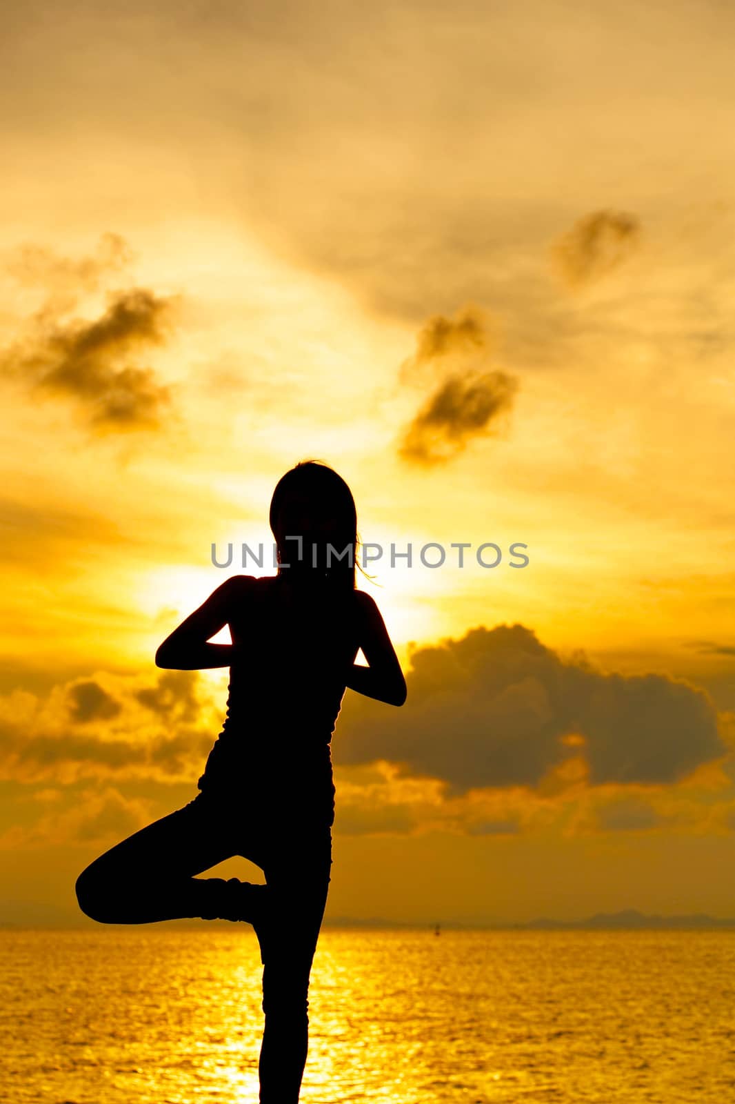 Woman doing yoga at sunset time