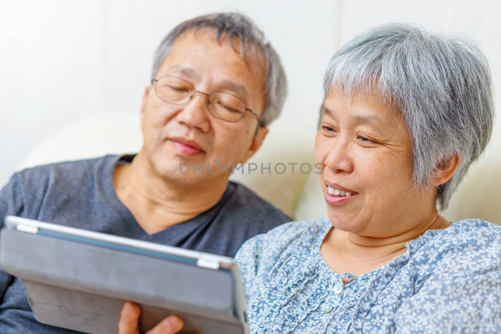 Asian elderly couple using digital tablet by leungchopan