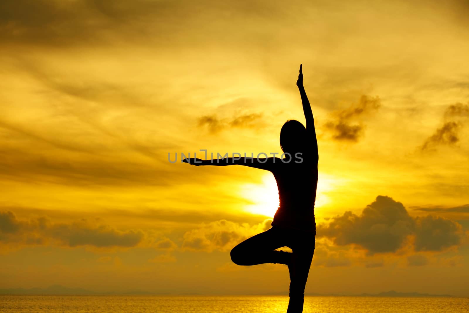 Woman doing yoga at sunset time