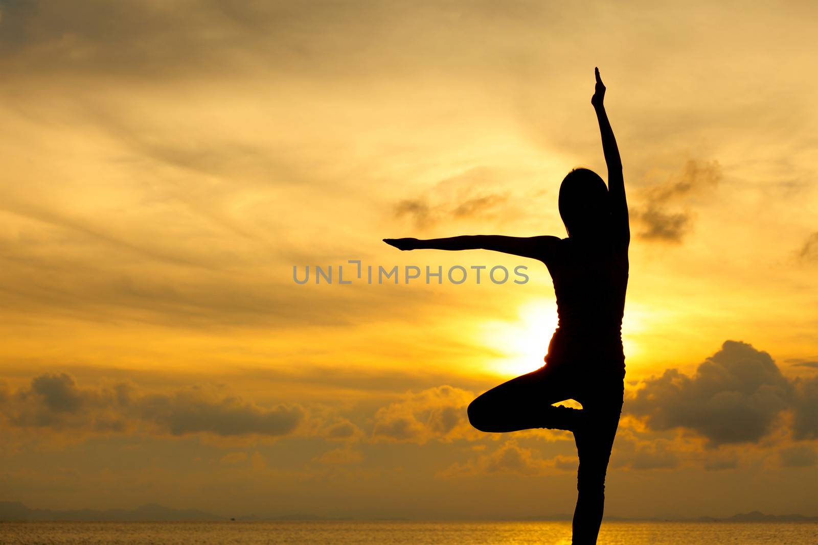 Silhouette of a woman yoga on sea sunset by leungchopan