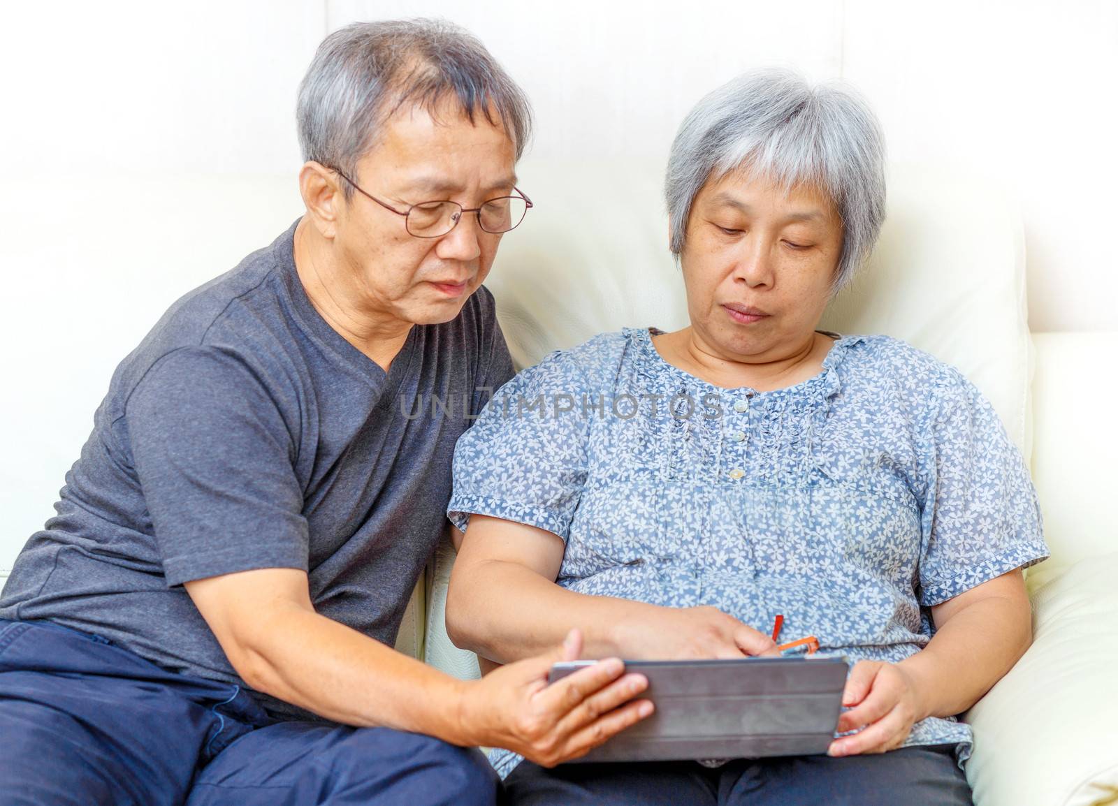 Asian elderly couple using digital tablet by leungchopan