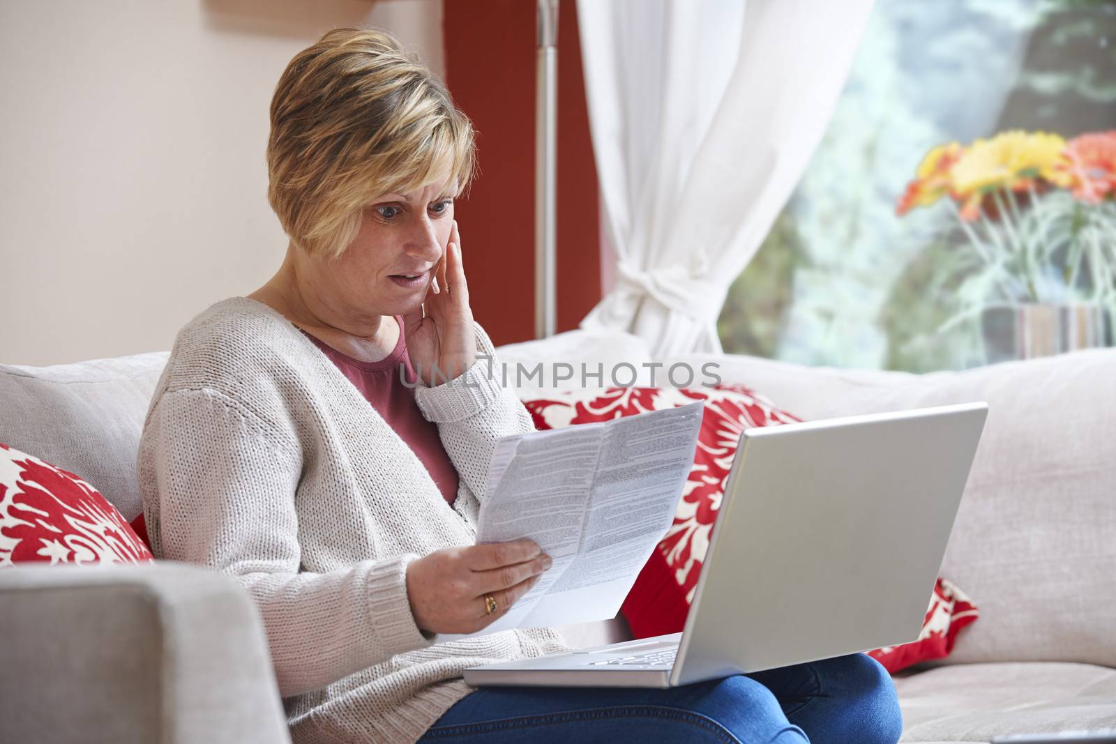 Worried woman looking at bill while on computer at home