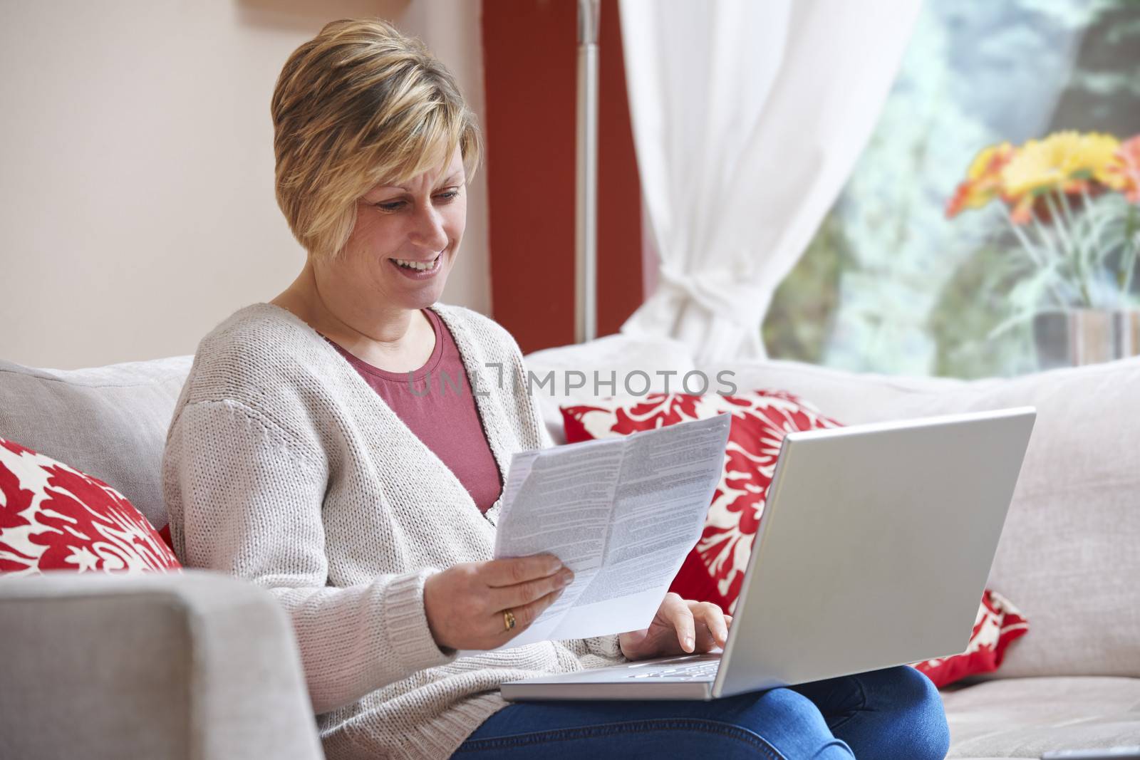 Woman looking happy while sitting at home doing home banking with laptop