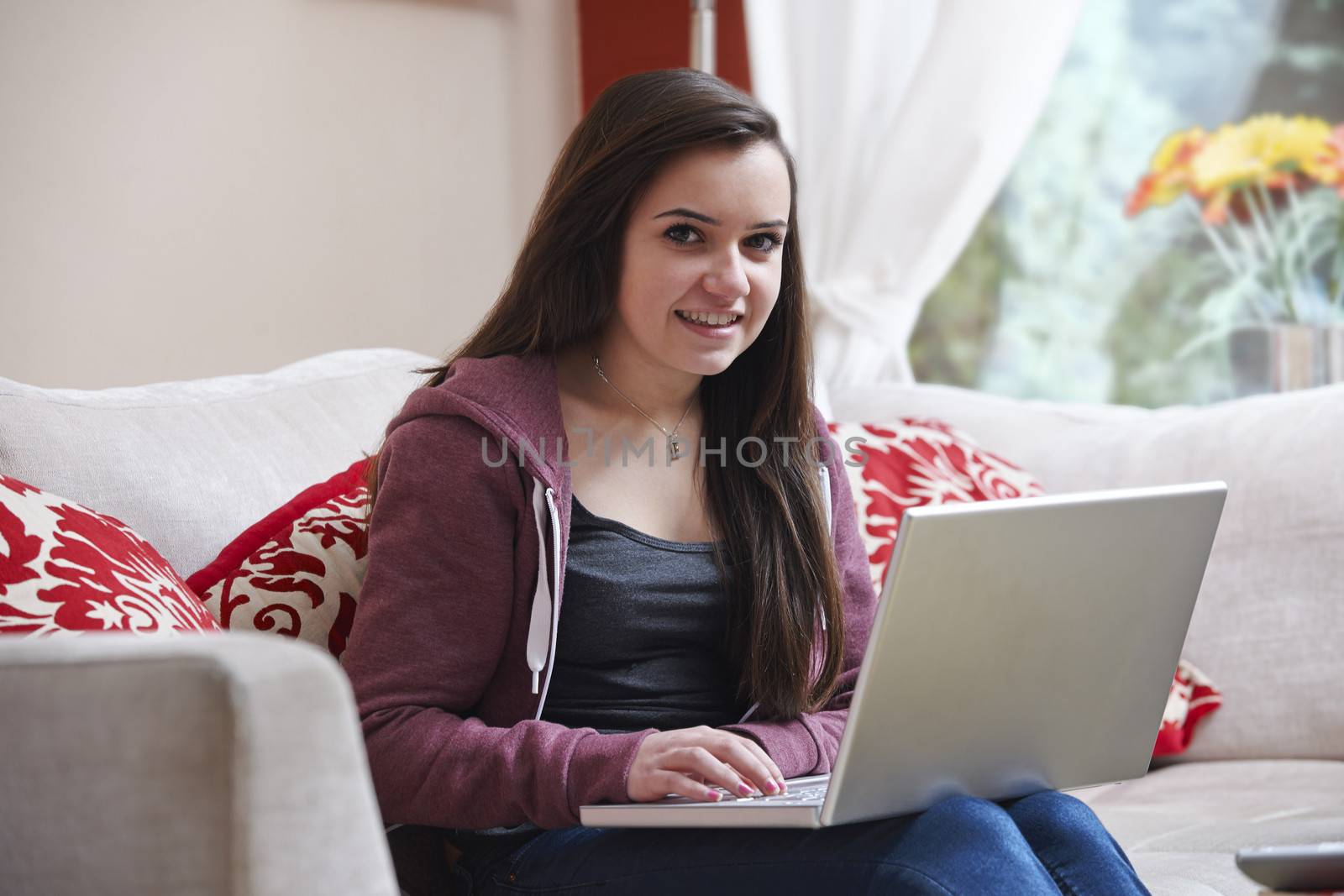 teenage girl smiling at camera while on laptop at home