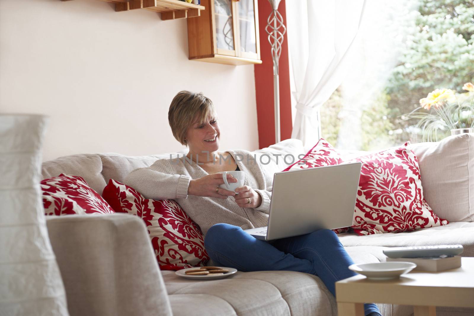Mother enjoying surfing on the net while relaxing at home with coffee