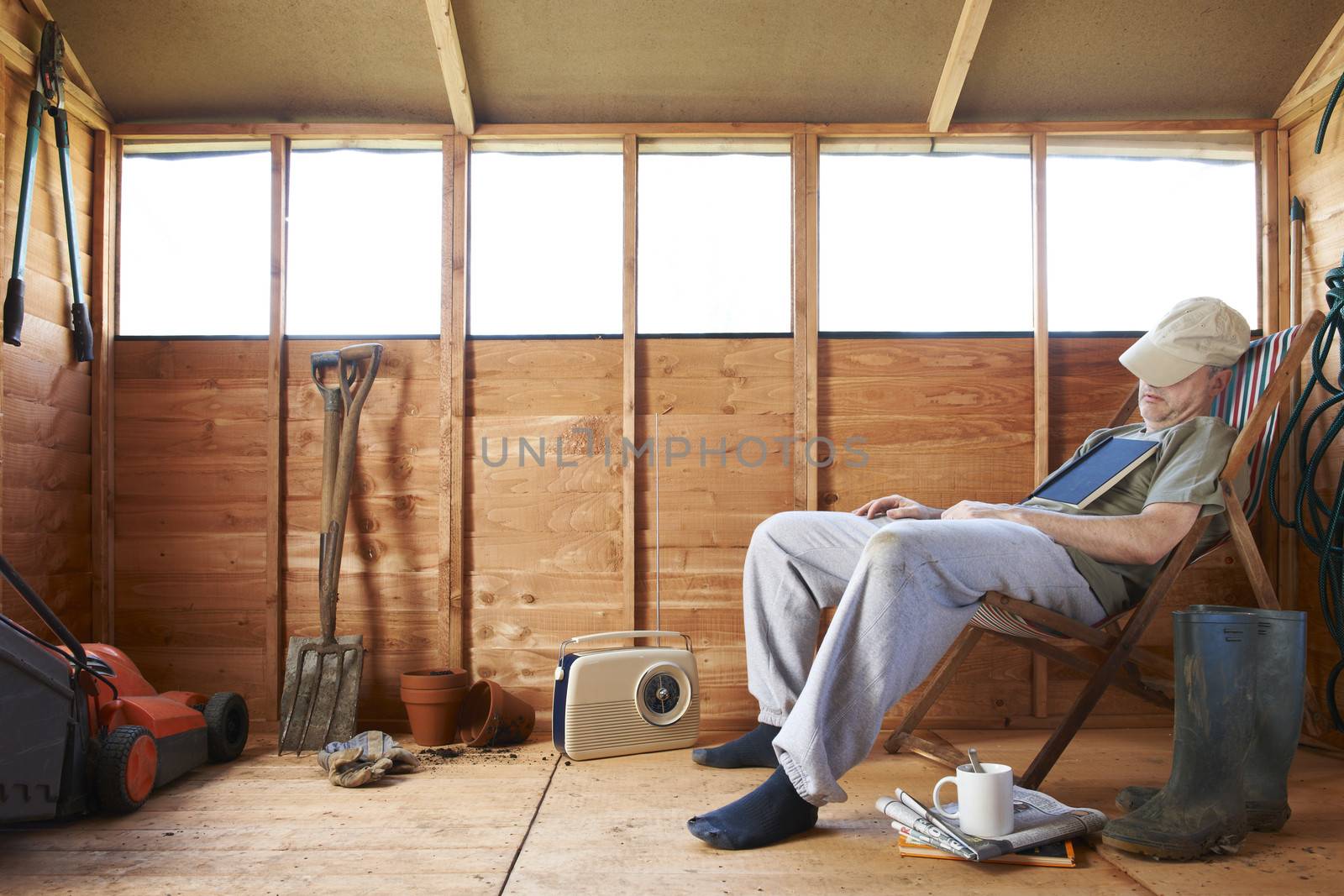 Man sitting in deckchair falling asleep in the shed