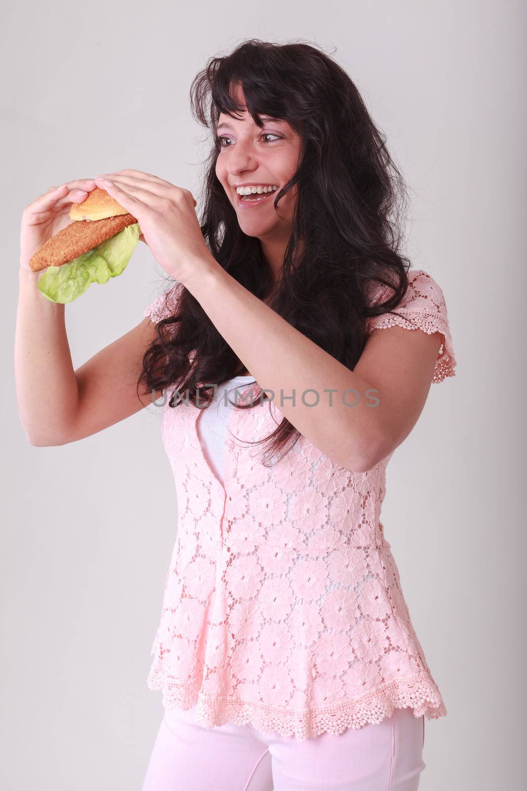 Young woman is a bun topped with Wiener schnitzel and salad