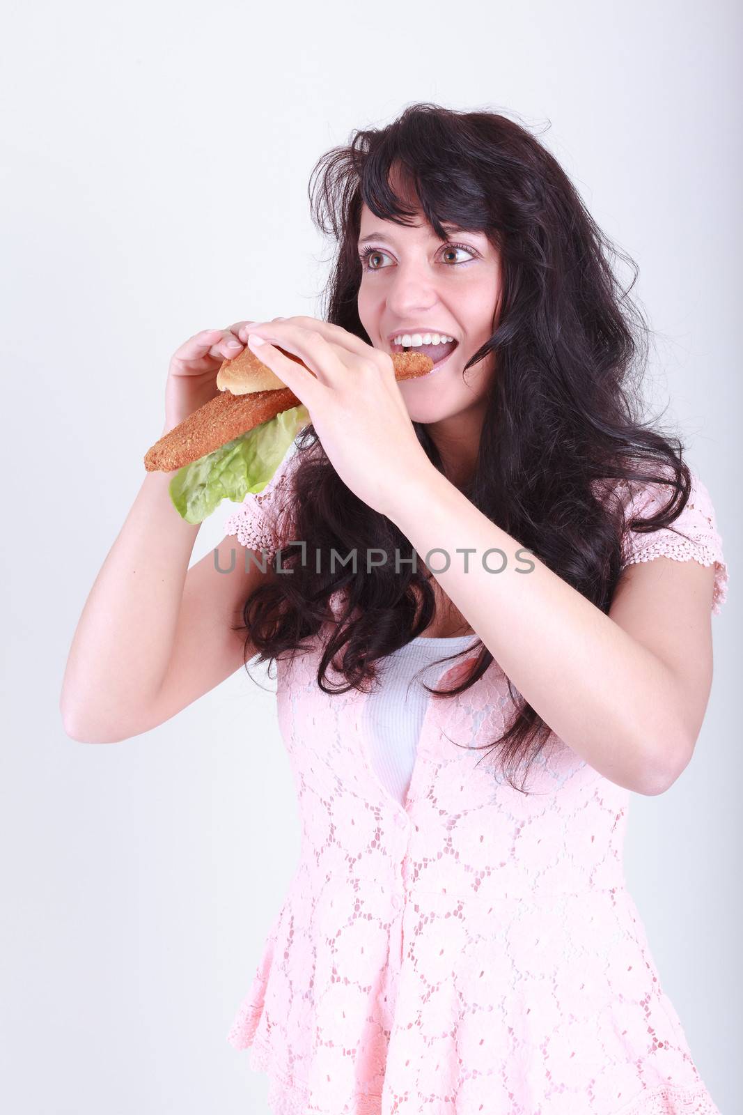 Young woman is a bun topped with Wiener schnitzel and salad