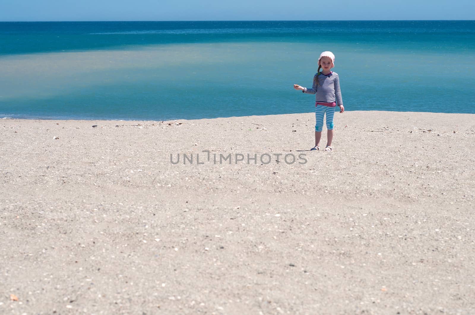 Little girl playing on the beach, coast and blue sea