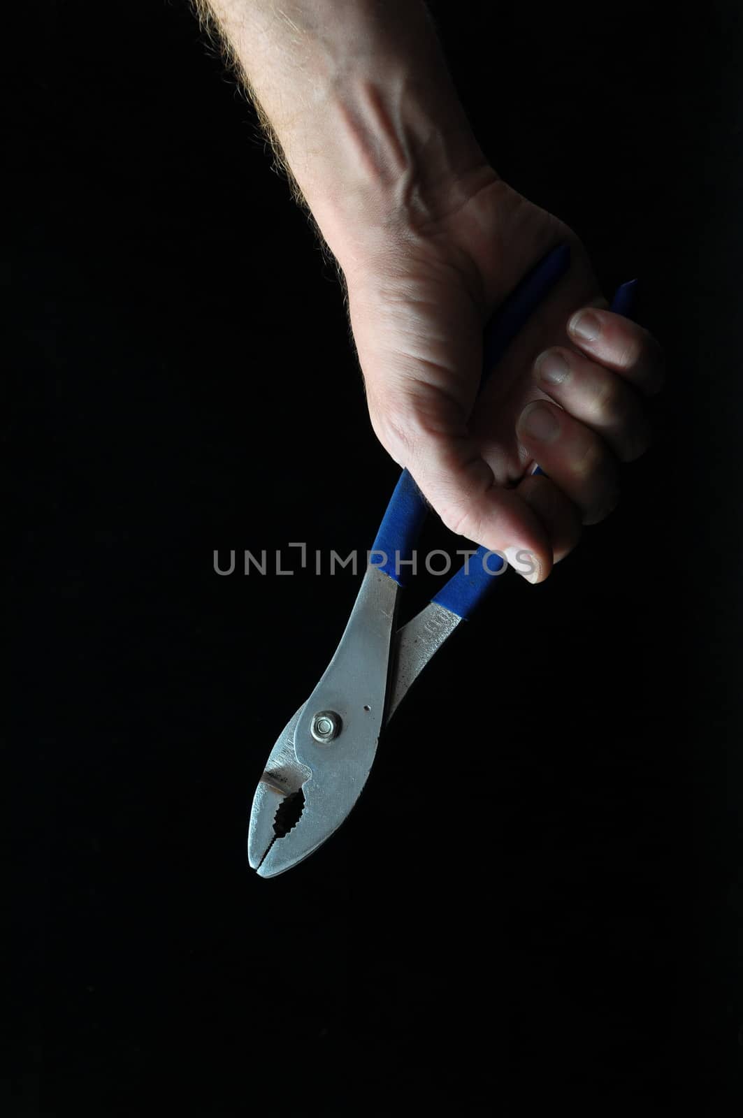 Pliers and a Hand on a Black Background