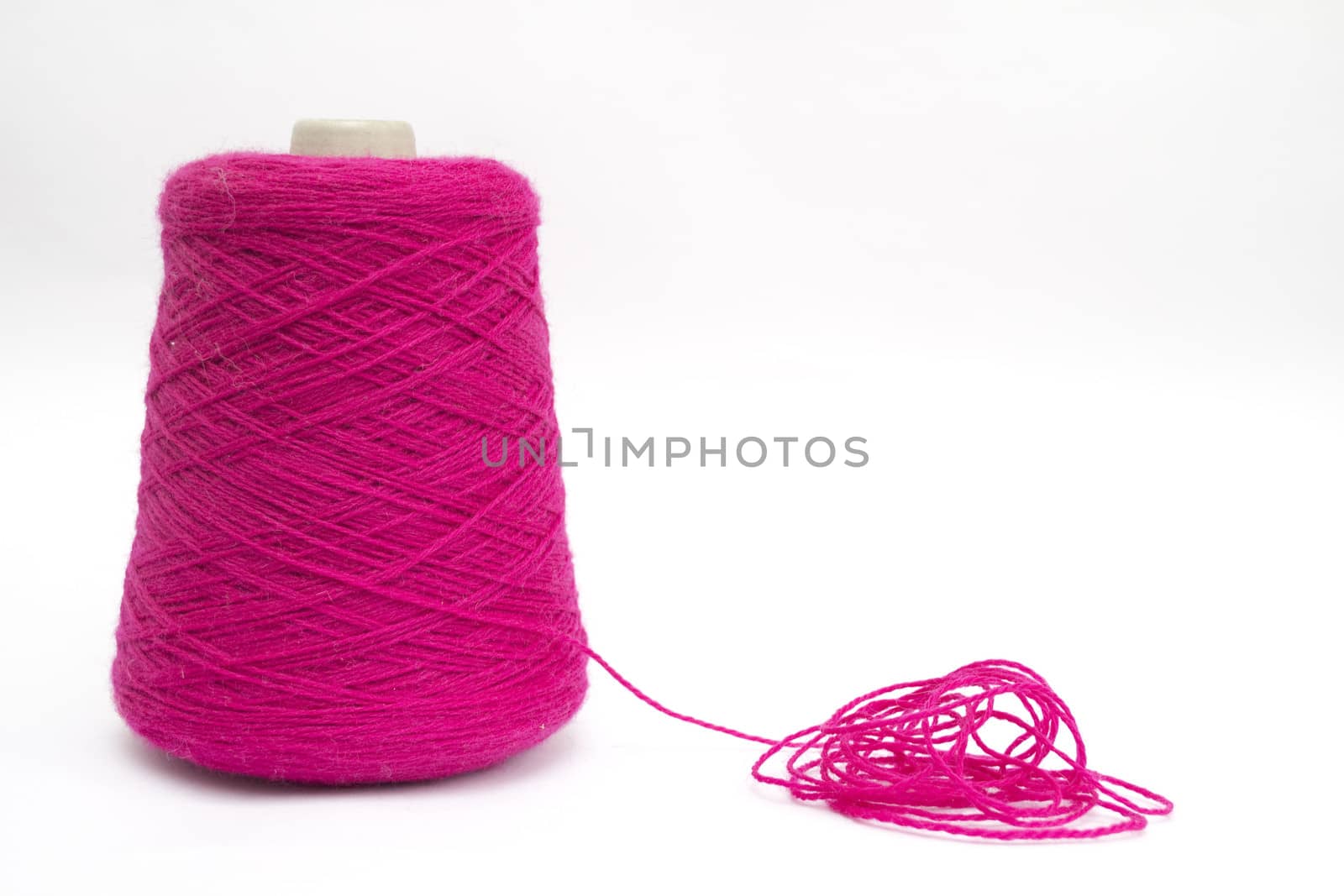 Cone of pink wool unravelled on a white background