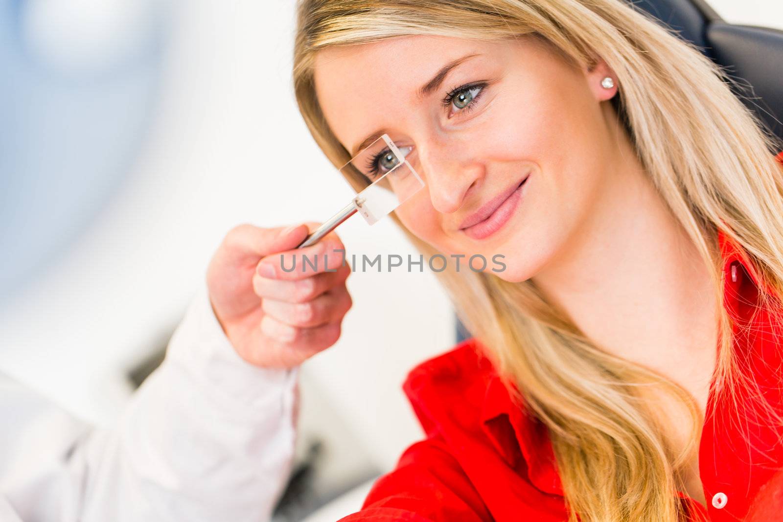 Optometry concept - pretty young woman having her eyes examined by an eye doctor (color toned image; shallow DOF)