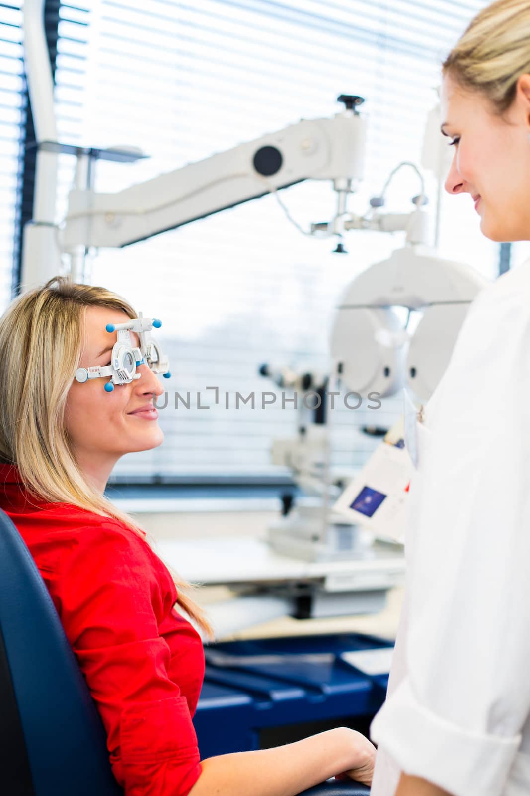 Optometry concept - pretty young woman having her eyes examined by an eye doctor (color toned image; shallow DOF)