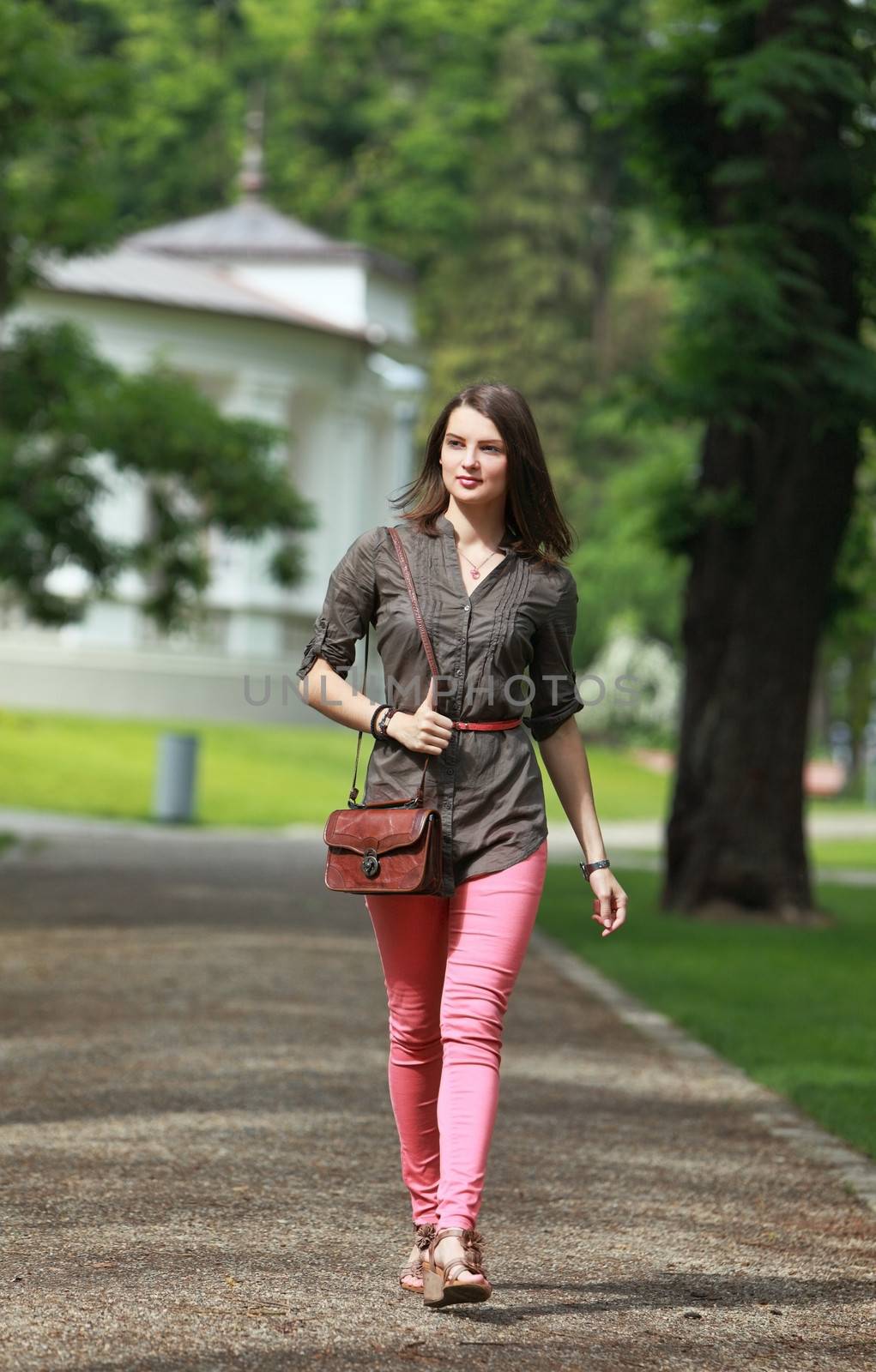 Beautiful young woman walking in a park in summer