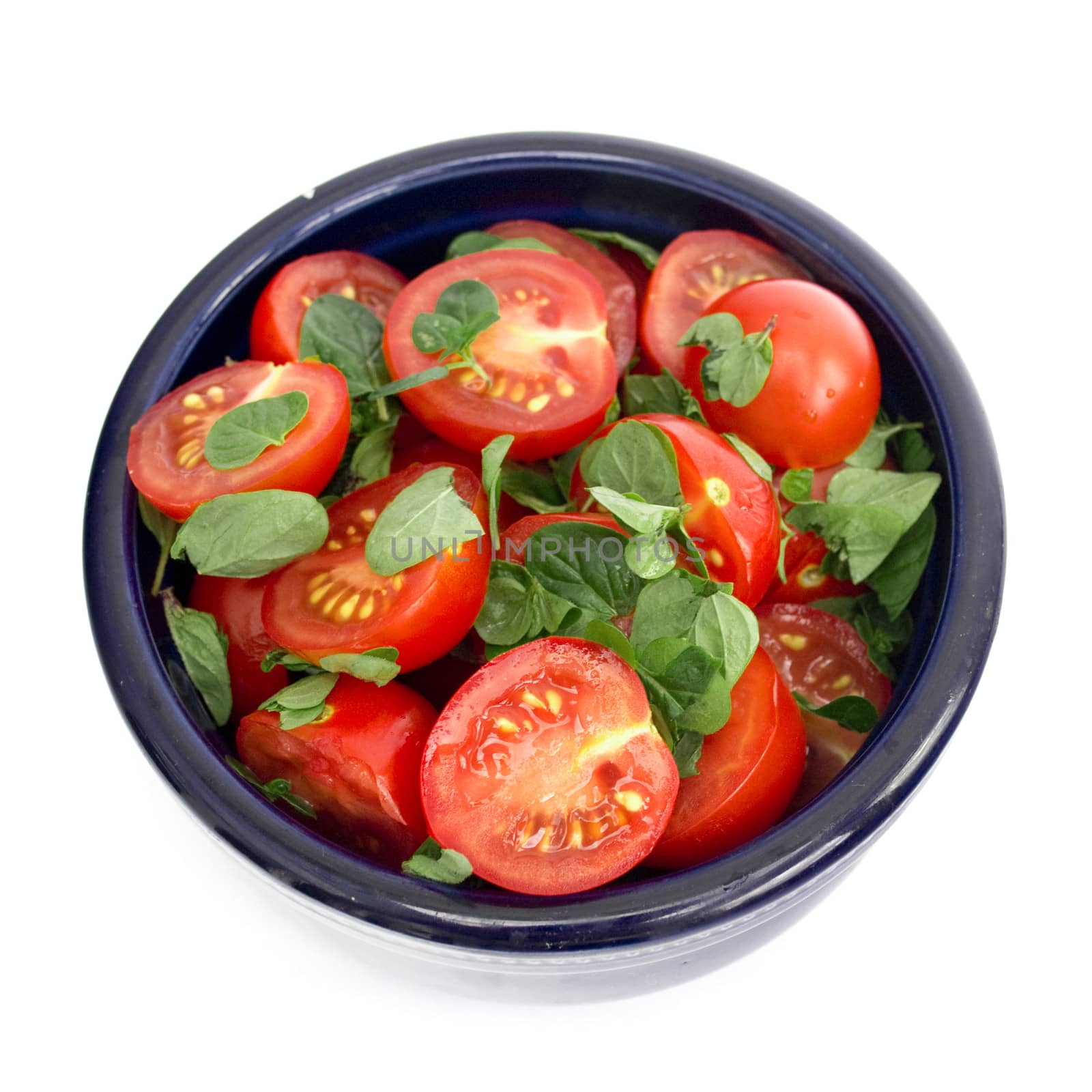 Tomatoes and basil in black bowl on a white background