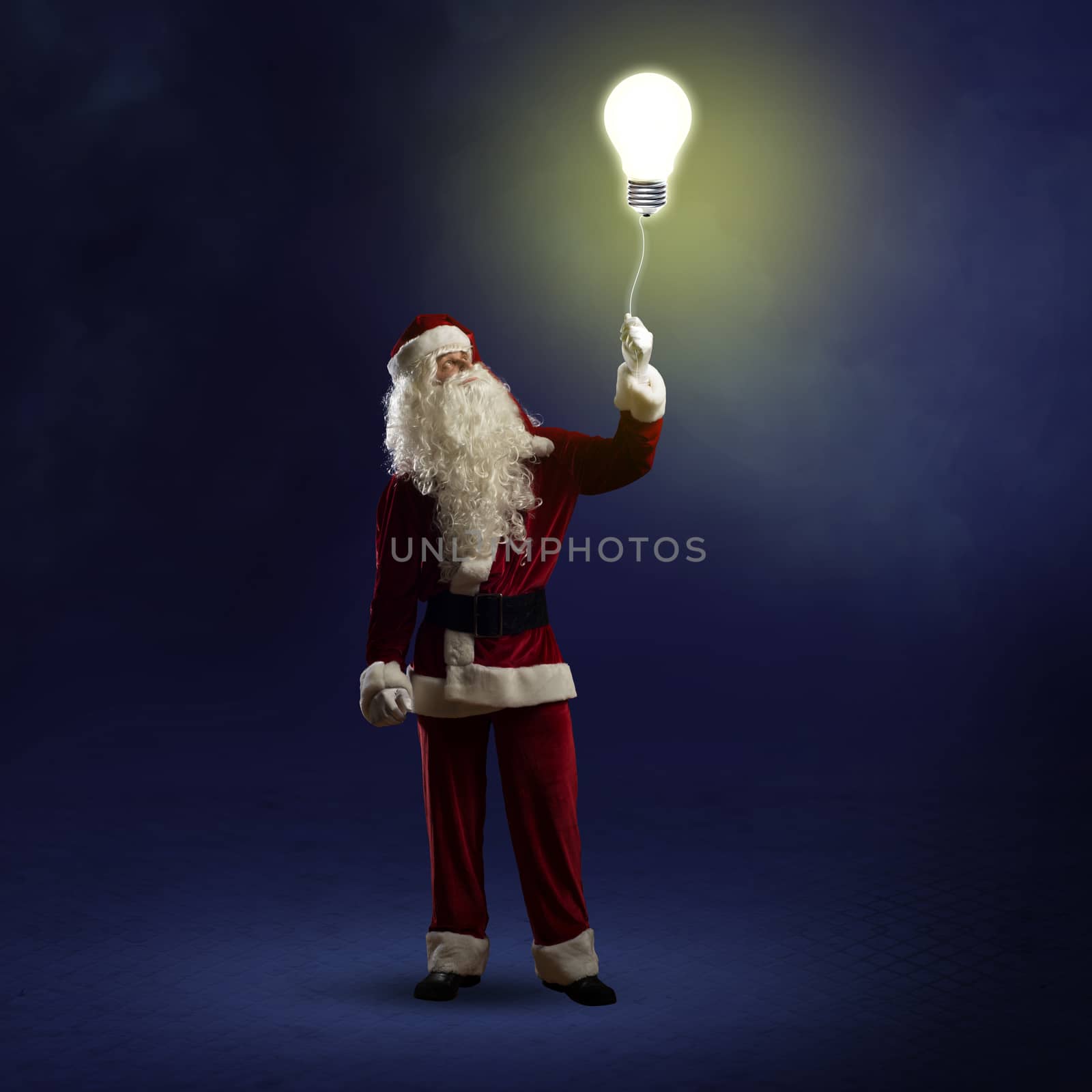 Santa Claus is holding a shining lamp on a string