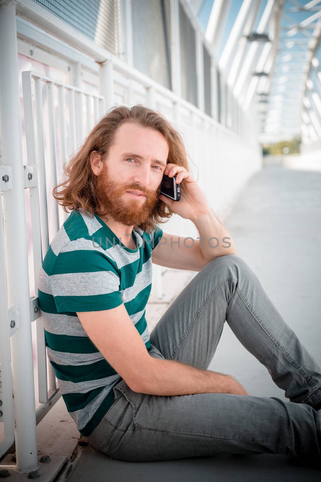 stylish hipster model with long red hair and beard lifestyle on the phone in the street