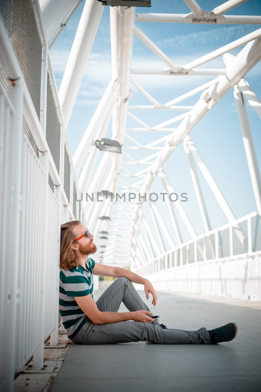 stylish hipster model with long red hair and beard lifestyle on the phone in the street