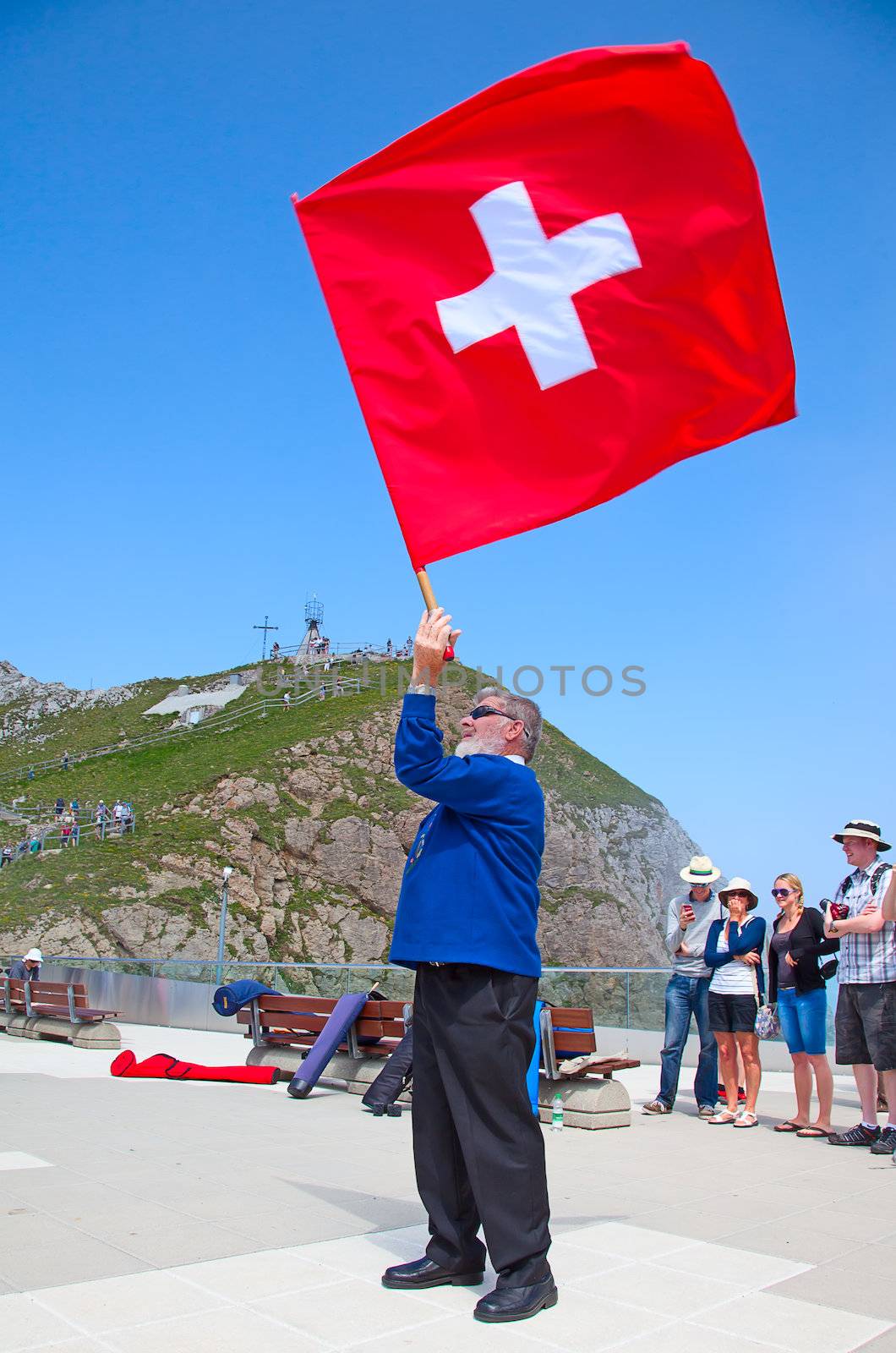 MOUNT PILATUS - JULY 13: Unidentified man demonstrating traditional swiss "flag throwing" on July 13, 2013 on the top of mount Pilatus, Switzerland. Flag twirling is one of the oldest national sports of Switzerland.