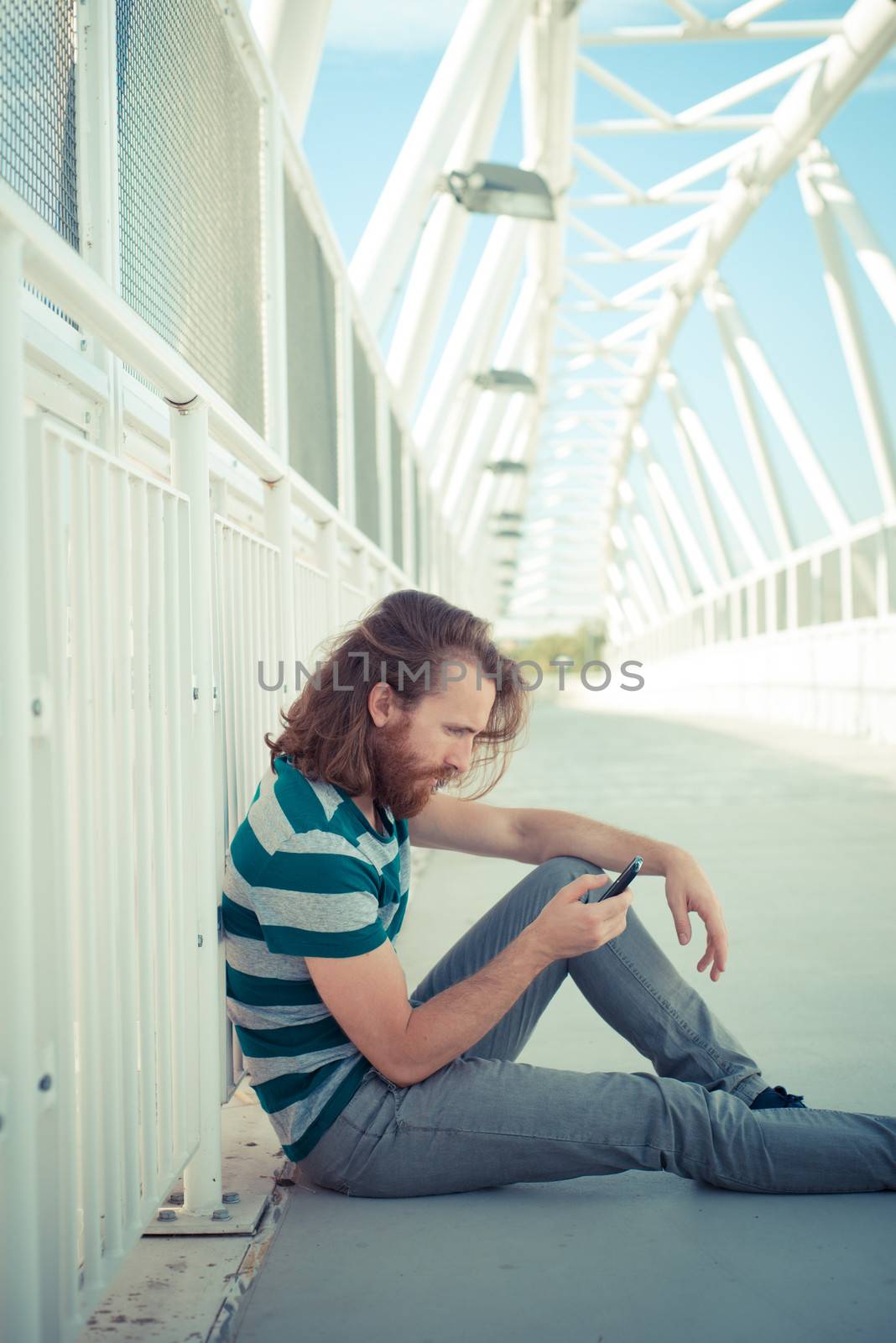 stylish hipster model with long red hair and beard lifestyle on the phone in the street