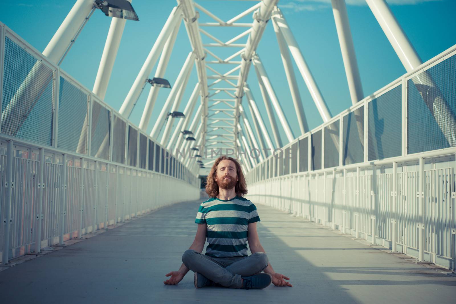 stylish hipster model with long red hair and beard yoga in the street