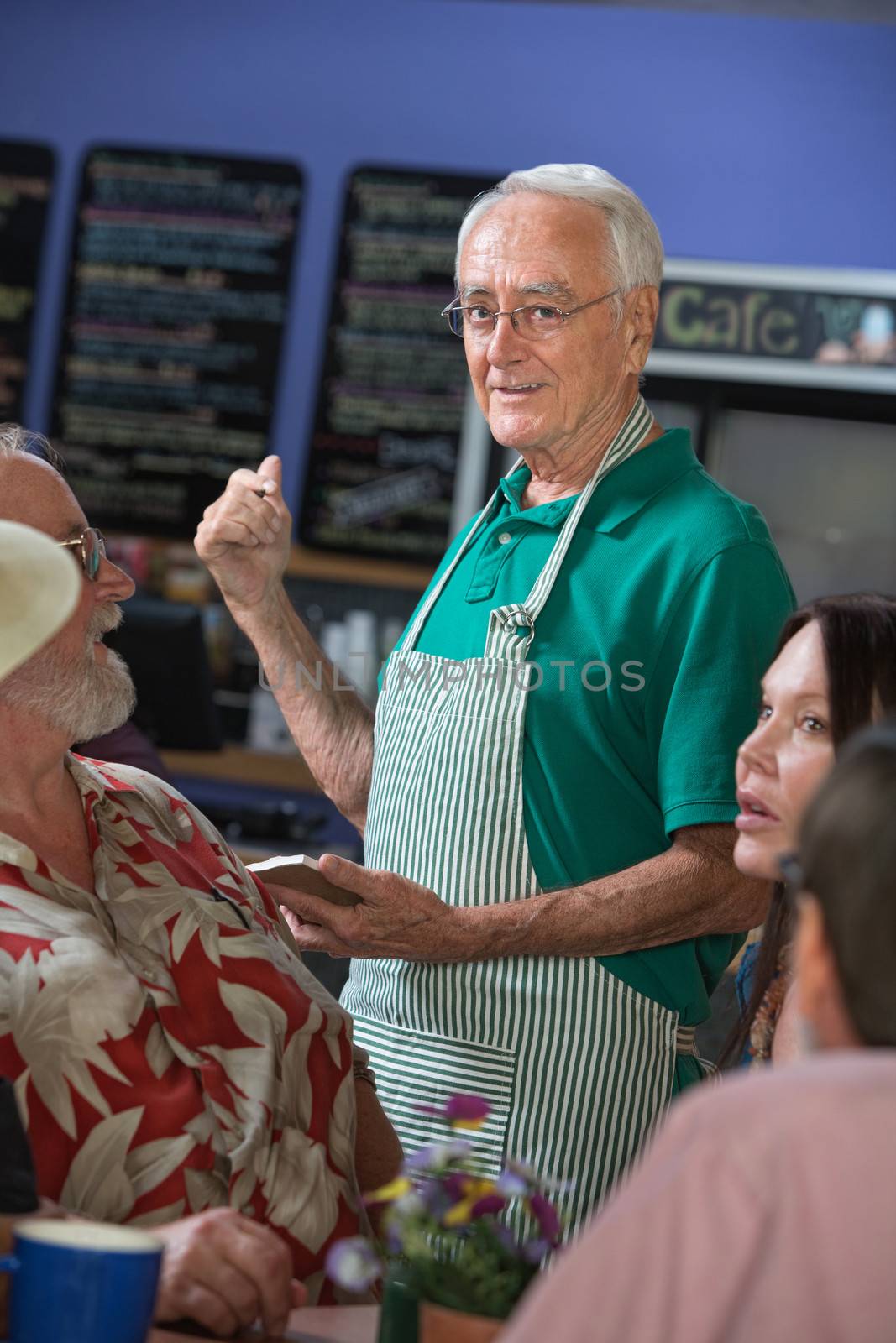 Handsome senior cafe host helping customers with order