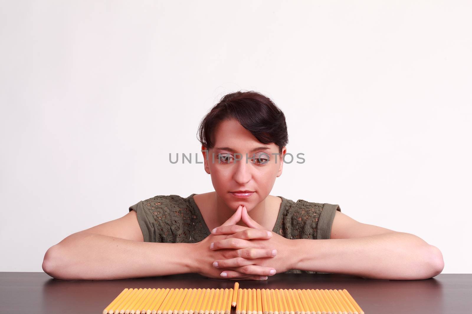 Young businesswoman staring at pencils and thinking