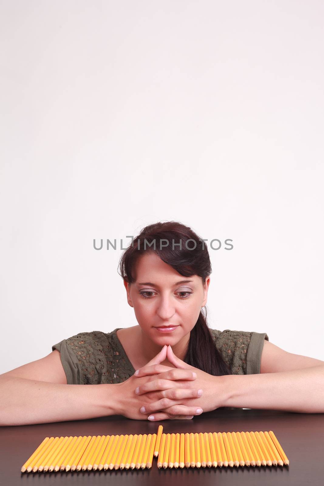 Young businesswoman staring at pencils and thinking