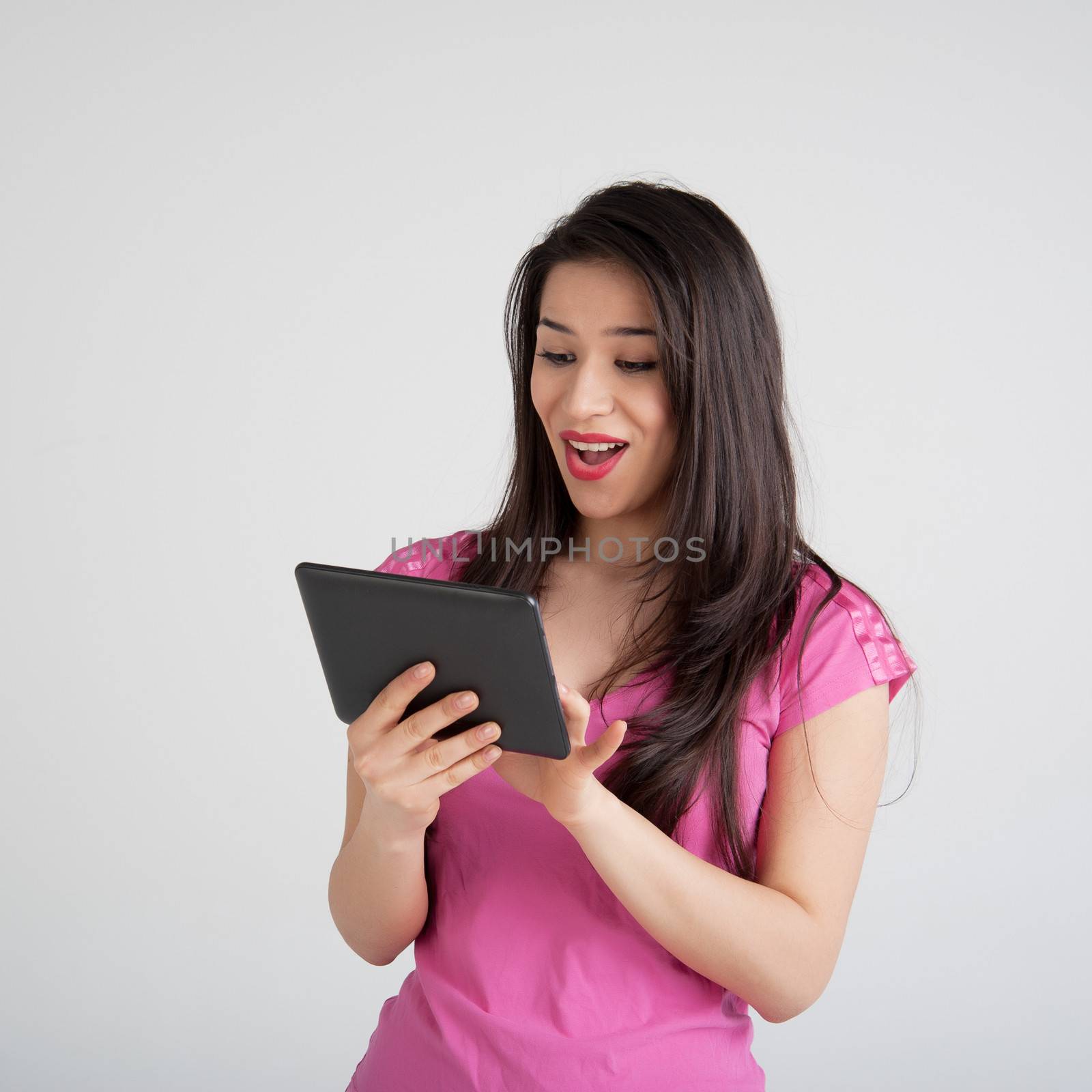 beautiful woman in pink t-shirt is pleased tablet