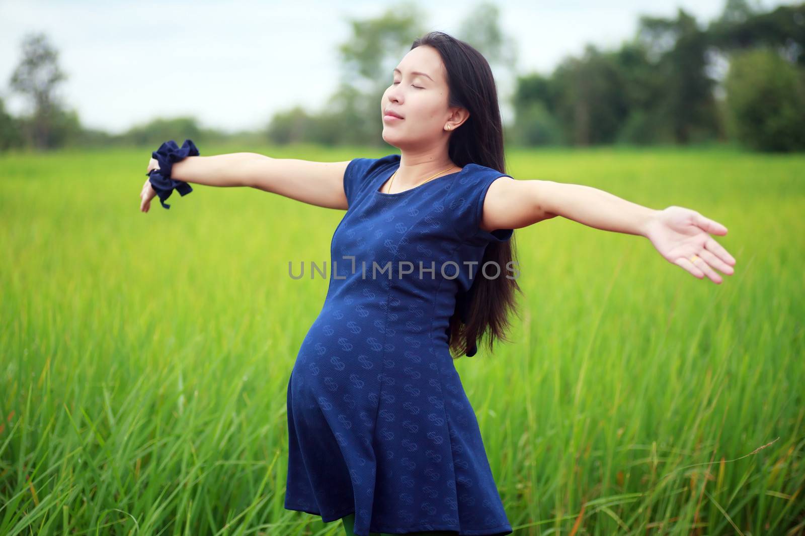 Pregnant woman on green meadow.